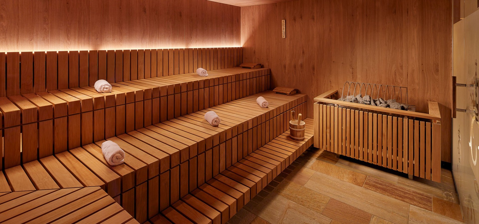 Geräumige Sauna mit gerollten Handtüchern auf den Sitzflächen platziert.