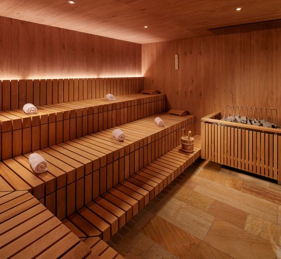 Geräumige Sauna mit gerollten Handtüchern auf den Sitzflächen platziert.
