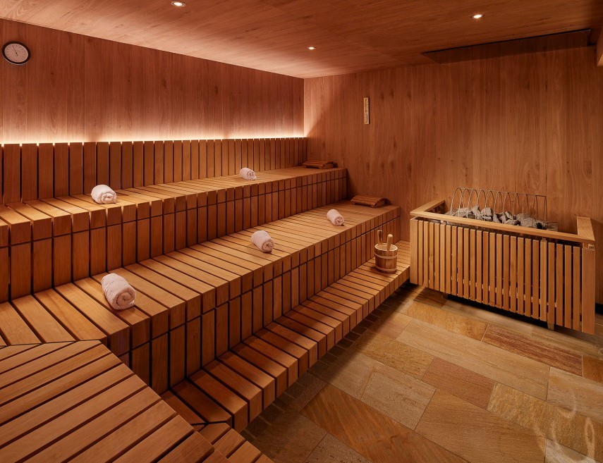 Sauna spacieux avec des serviettes roulées placées sur les sièges.